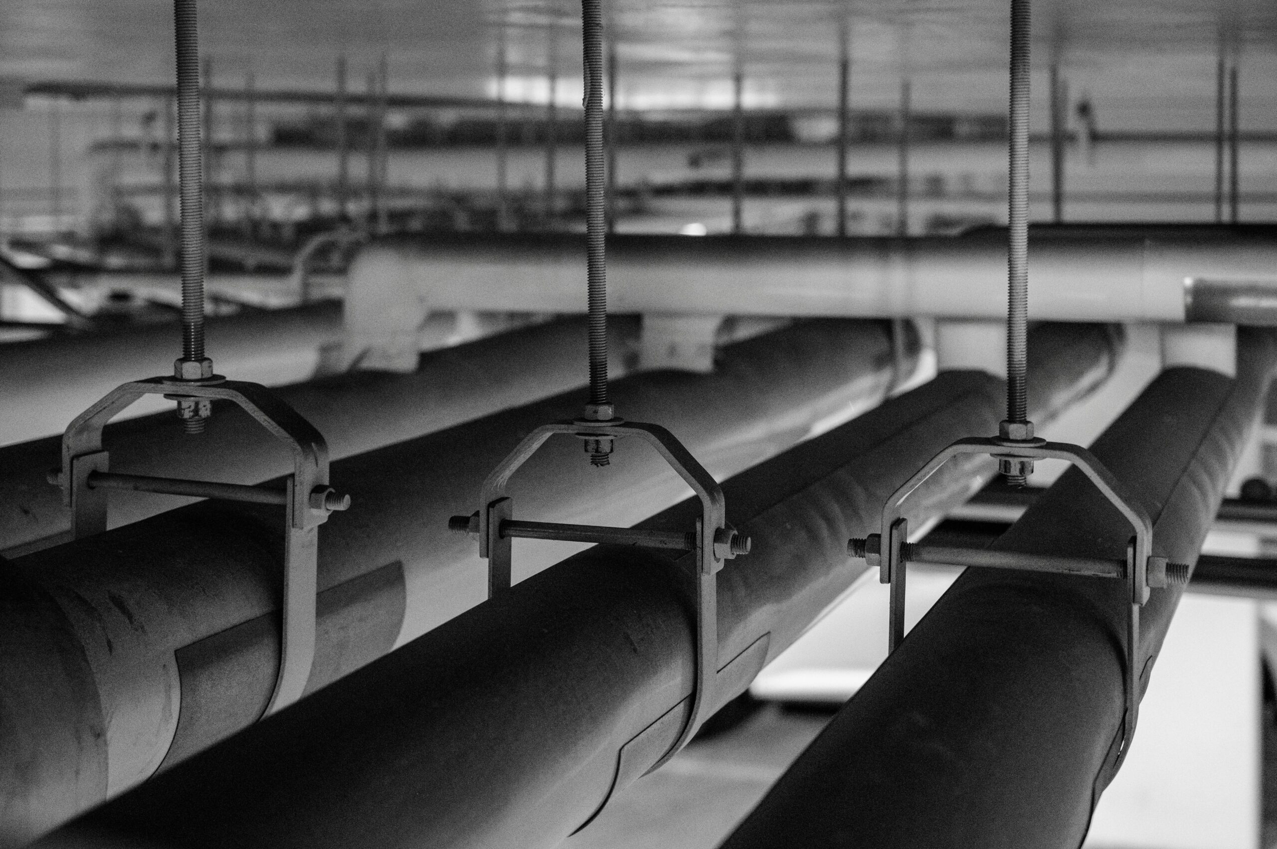 Black and white photo of industrial pipes and fittings, captured in a production facility.