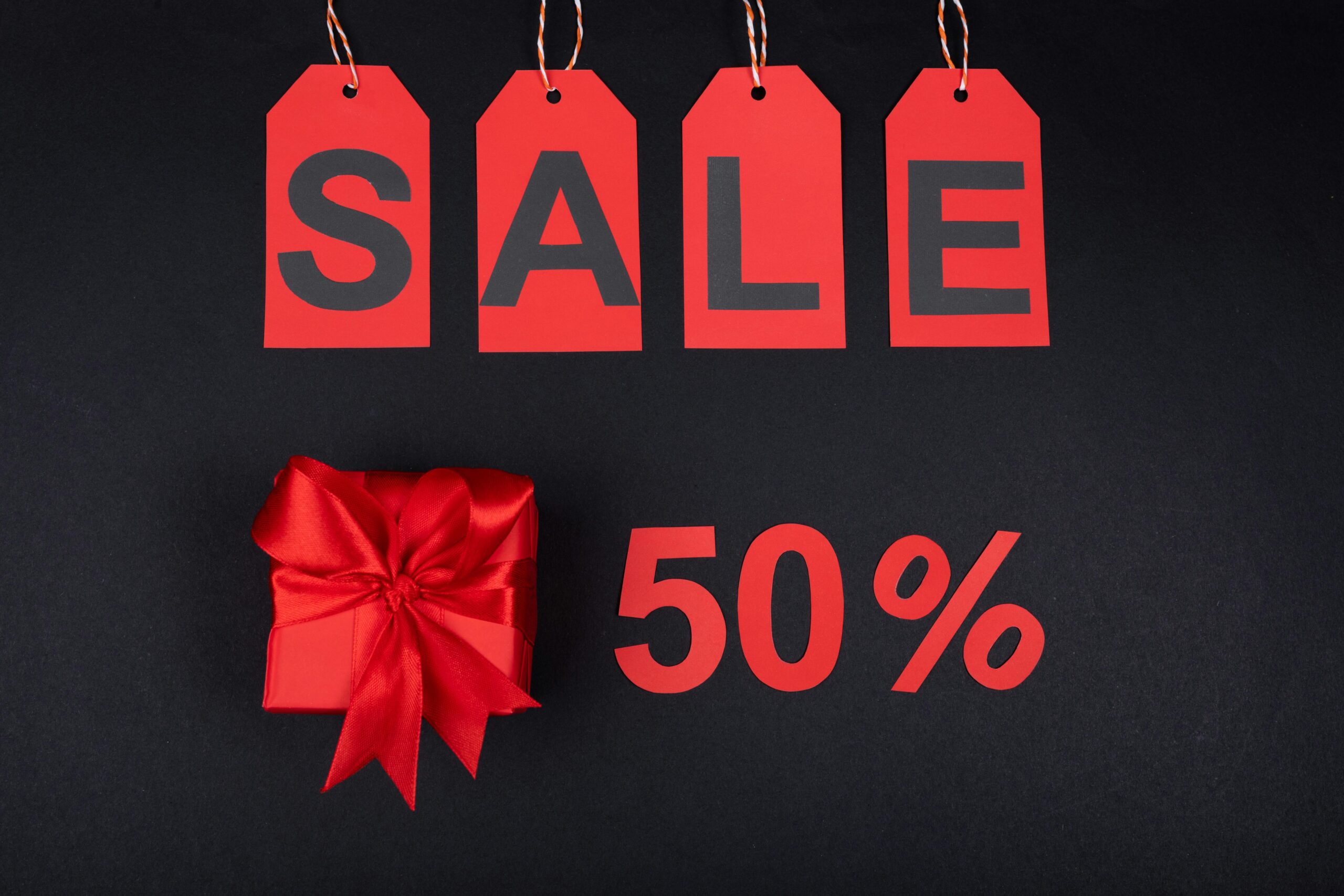 Pricing Red sale tags and gift box on black background emphasizing 50% discount for promotions.
